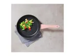 Black frying pan with a pink handle, filled with stir-fried vegetables, on a grey napkin.