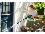 Woman cleaning a blue door with a PARKSIDE cordless pressure washer