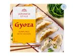 Japanese style chicken gyoza dumplings on a plate with chopsticks and a side of greens, frozen.