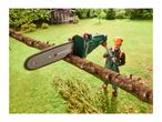 A man in safety gear uses a pole saw to cut a tree branch in a garden.