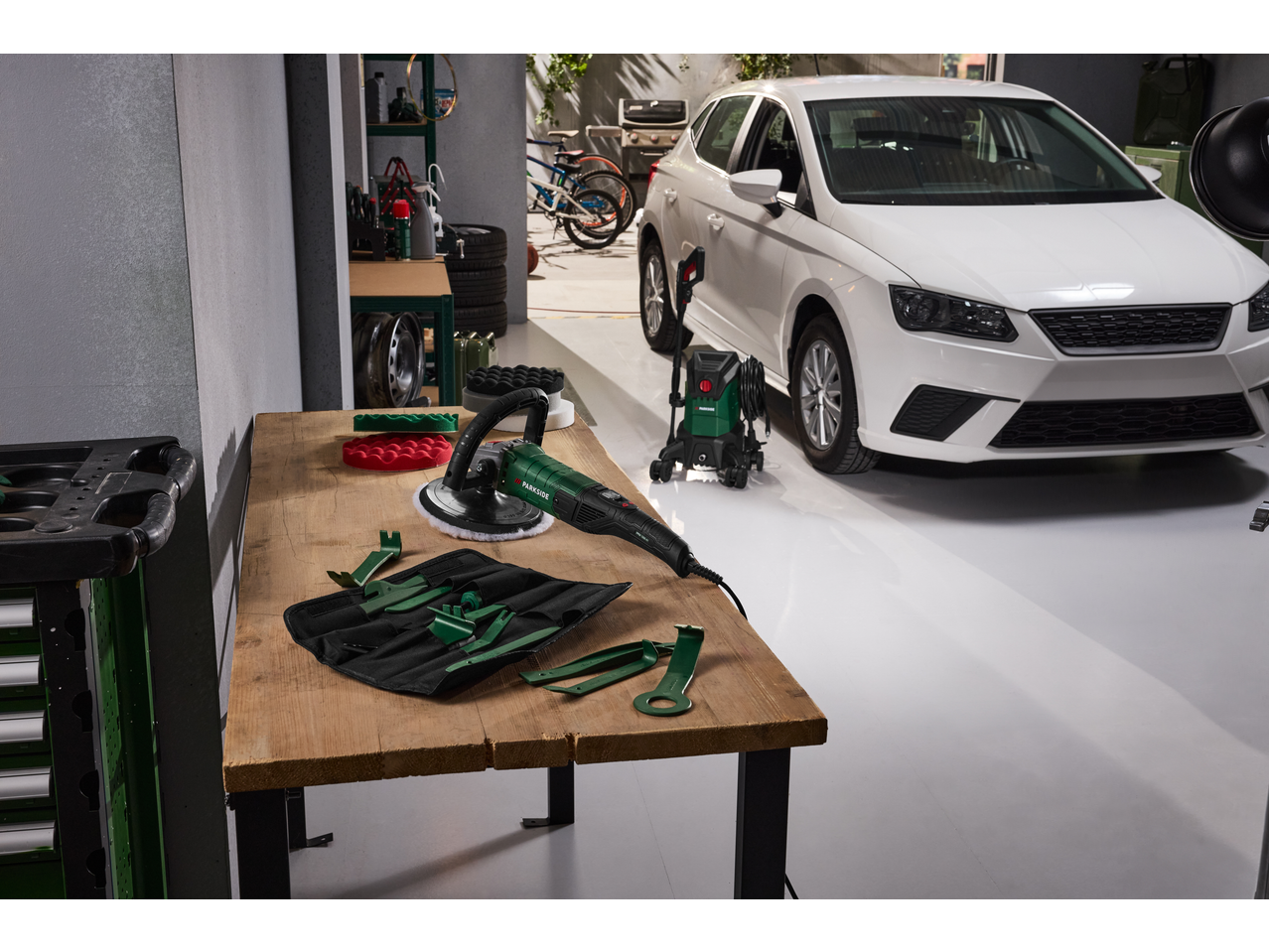 Mașină de lustruit PARKSIDE și set de demontare tapițerie pe o masă într-un garaj cu o mașină.