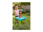 Child playing with a water and sand table in a garden, pouring water into a toy.