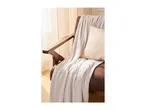 A cozy brown armchair styled with a soft knit throw blanket and a cream-colored pillow.