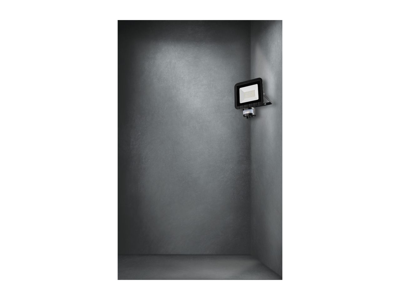 A black LED floodlight with a motion sensor mounted on a gray concrete wall.