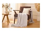 Cozy brown armchair with a soft throw blanket and cushion in a warm, modern living room.