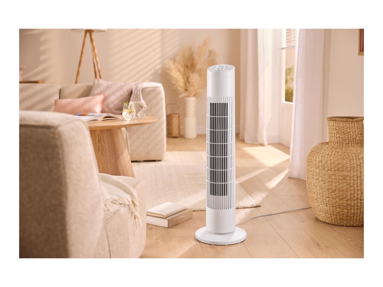 White tower fan in a bright living room with a sofa, coffee table, and woven decor.