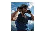 Man in cycling helmet, sunglasses, and gloves, adjusting helmet with mountains in background.
