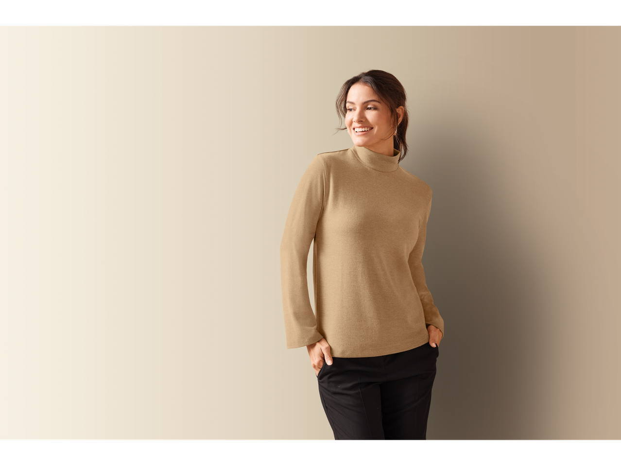 Smiling woman wearing a beige Esmara turtleneck and black pants.