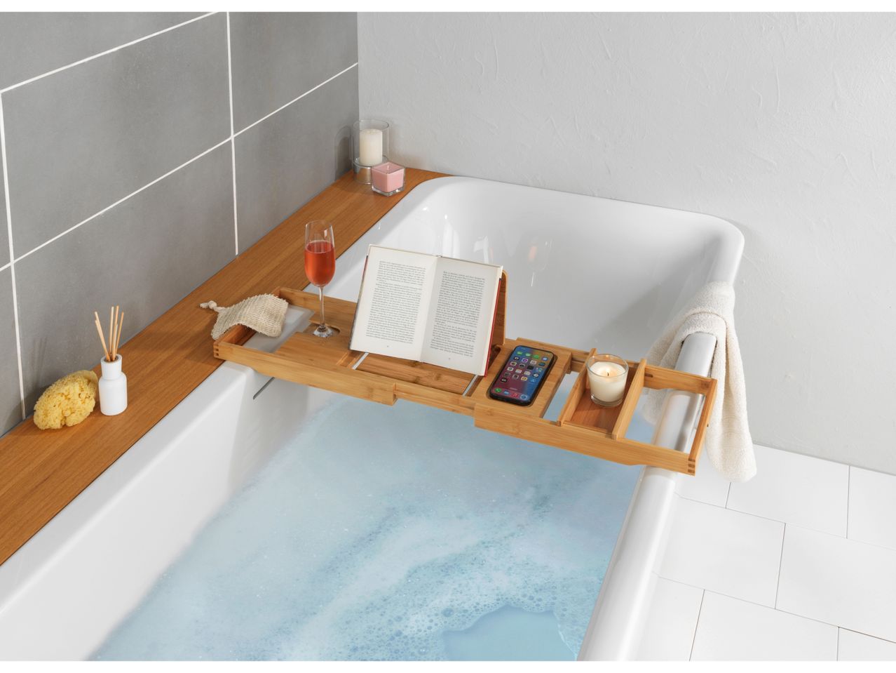 Bamboo bathtub tray with book, candles, and phone.