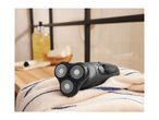 Black electric shaver with three rotary blades on a striped towel in a bathroom.