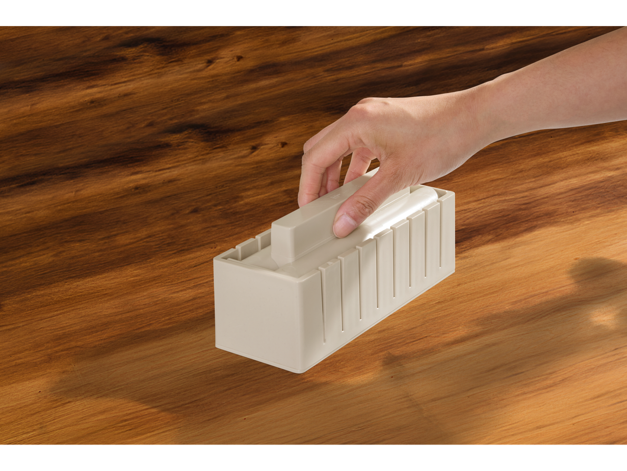 Mão a usar o kit de sushi Silvercrest numa superfície de madeira.