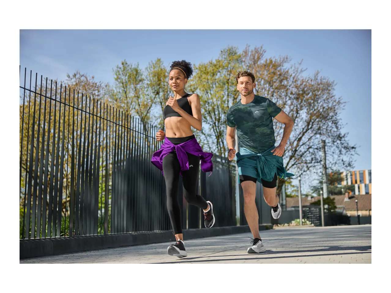 Two people running outdoors, wearing sports tops, leggings, and shorts.