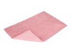 Pink rectangular bath mat with a textured, bobble surface and a folded corner revealing the underside.