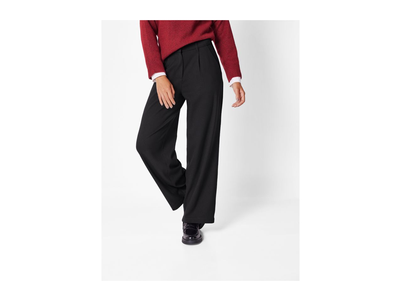 A person wearing a red sweater, black wide-leg trousers, and black loafers.