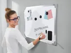 Eine Frau schreibt auf einer weißen Magnettafel mit Zubehör.