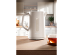 A white Silvercrest kettle sits on a wooden counter next to a cup of tea.