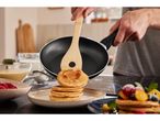 Wooden spatula flipping pancakes in a non-stick frying pan.