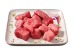 Frische Rinderwürfel auf einer Platte mit Zwiebeln und Kräutern.