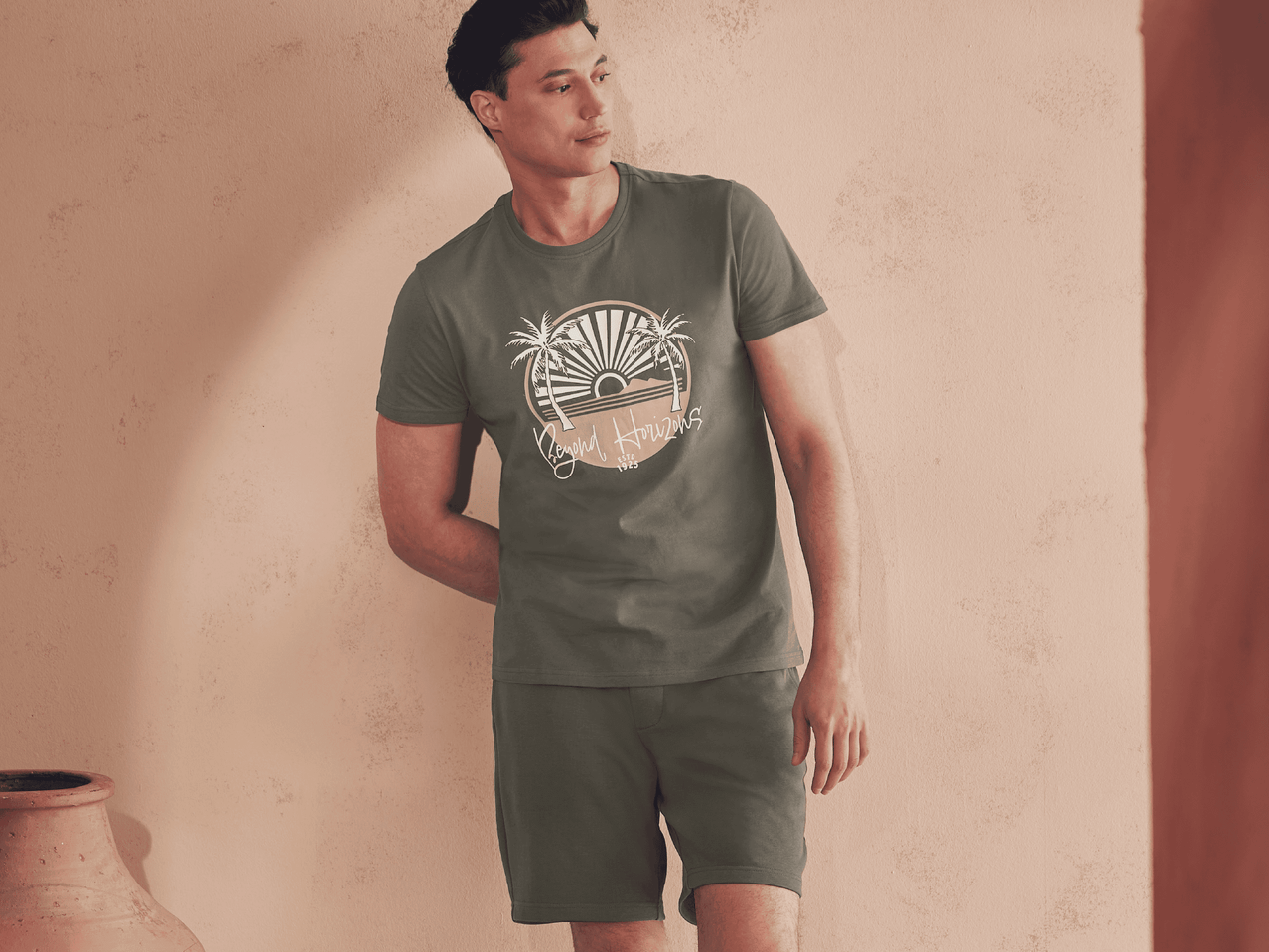 Mann in olivgrünem T-Shirt und Shorts mit Palmenmotiv.