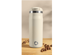 Termo de café bege com grãos de café numa mesa de madeira.