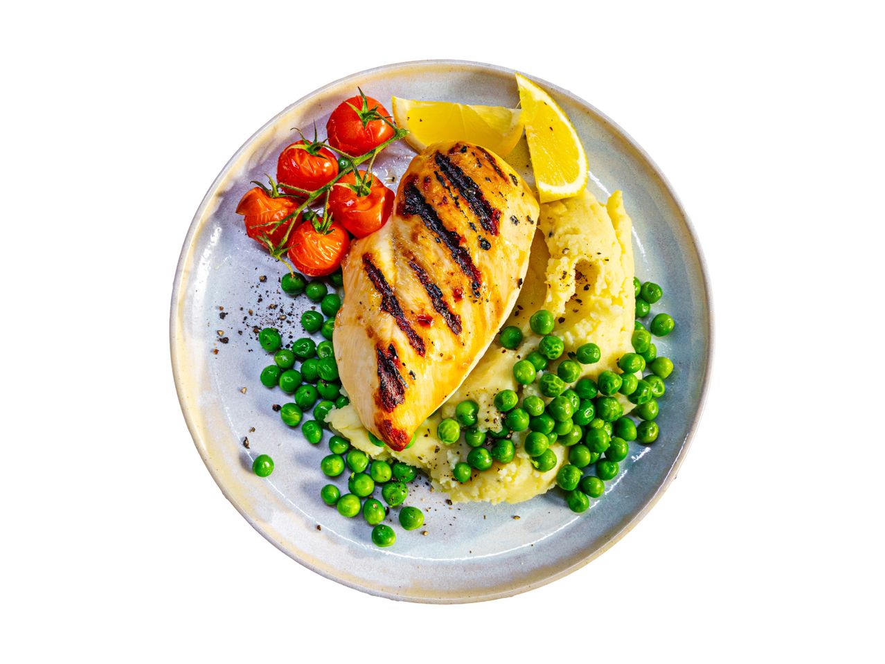 Grilled chicken breast with mashed potatoes, green peas, roasted tomatoes, and lemon wedges.