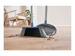A broom and dustpan sweep up dirt on a wooden floor.