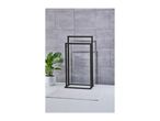 Black metal towel rack with a potted plant and a white bath mat on a white surface.