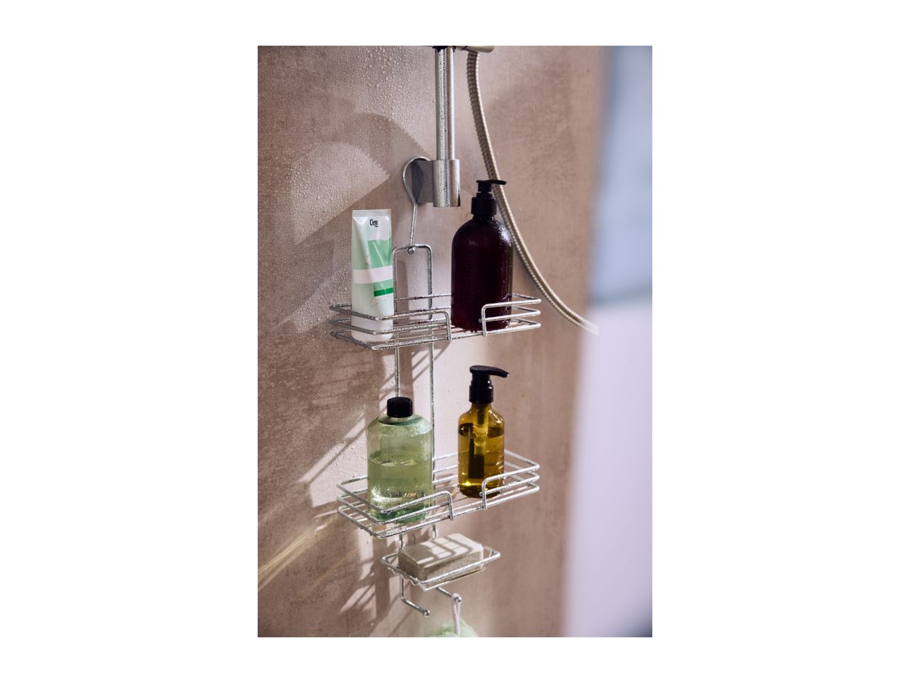 Shower caddy with various shower gels, shampoo, and soap on a wet shower wall.