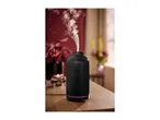 Black ribbed aroma diffuser emitting mist on a wooden table