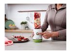 Person blending fruit in a personal blender on a kitchen counter.