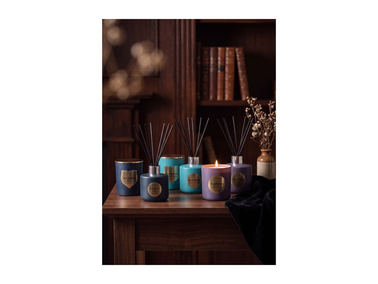 Scented candles and reed diffusers on a wooden table in a cozy, classic room.