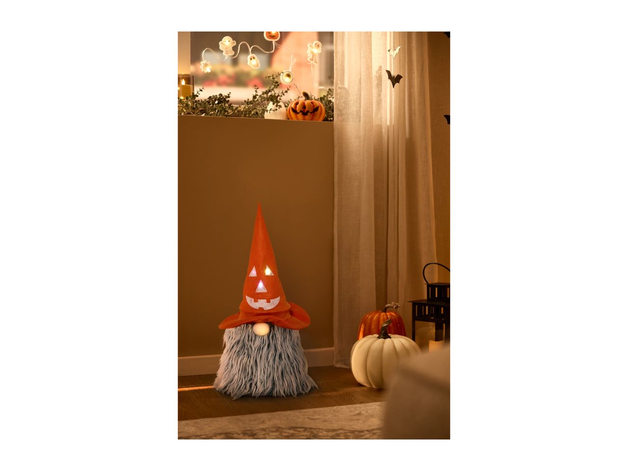 Halloween gnome with a glowing orange hat next to decorative pumpkins