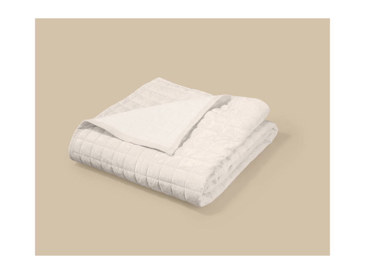 Folded beige quilted blanket on a light brown background