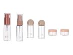 A set of Cien Beauty clear plastic travel bottles and jars with light brown and pink caps.