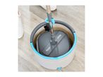 Minky mop and bucket with dirty water on a wooden floor, with a person's white shoe visible.