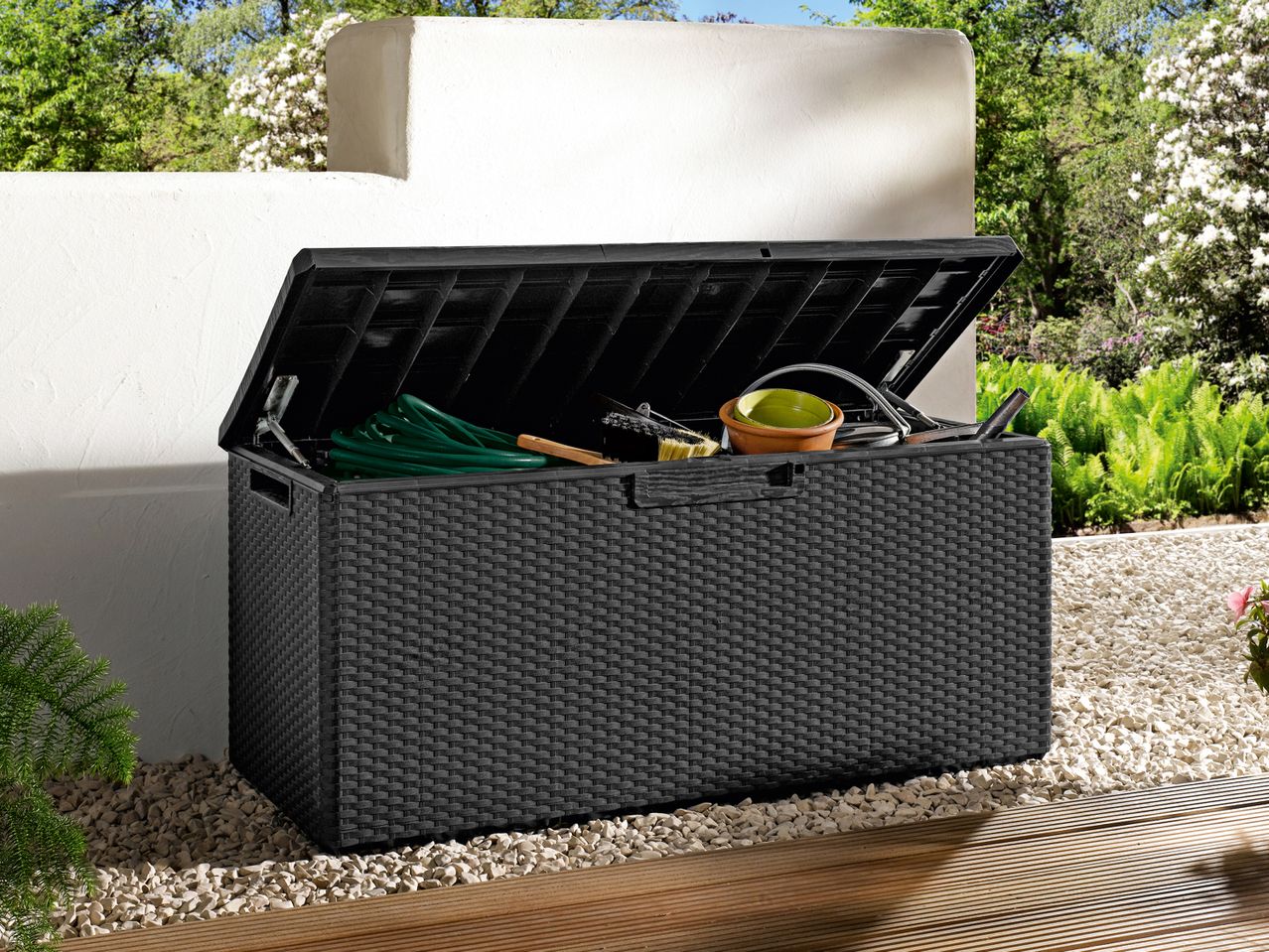 Black rattan-style garden storage box with an open lid, filled with gardening tools.