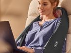 Жена с масажор за врат и рамене Sensiplast, работеща на лаптоп.