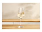 A glass of white wine with a slight ripple, on a wooden countertop in a kitchen.