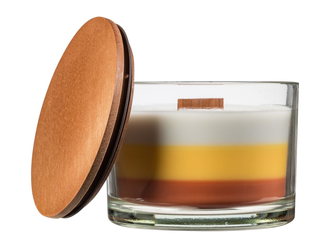 A layered candle in a glass jar with a wooden lid leaning against it.