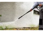 A person uses a Parkside® pressure washer to clean a white wall.