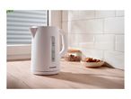 White electric kettle on a wooden kitchen counter with cookies and a jar of sugar.