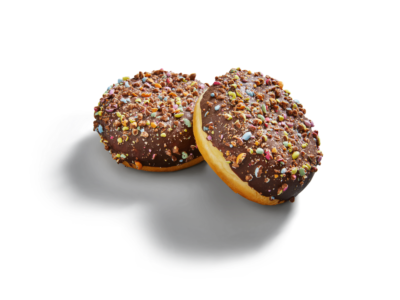 Zwei Schoko-Donuts mit bunten Streuseln liegen auf einer dunklen Fläche.