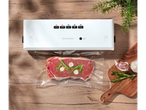 Máquina de vácuo Silvercrest com carne embalada a vácuo, alho e alecrim numa mesa de madeira.