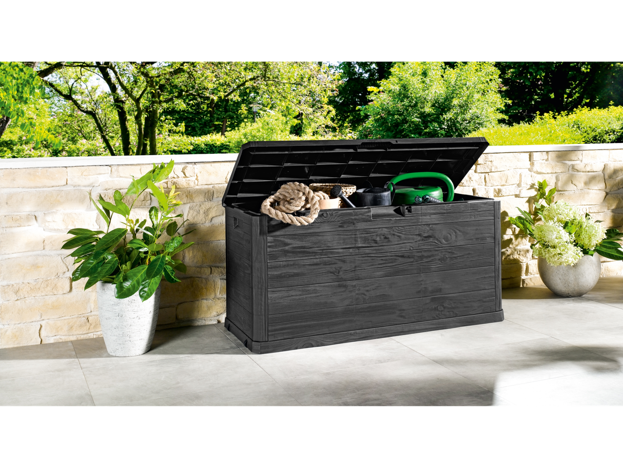 Coffre de rangement Keter gris foncé pour jardin, avec outils de jardin.