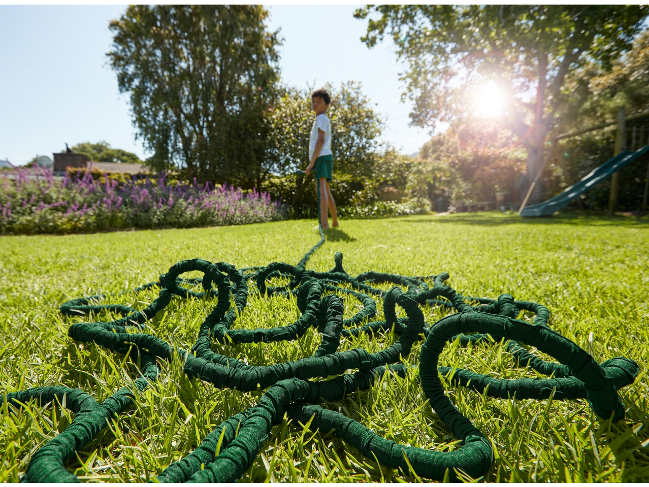 Parkside® 15m Flexible Garden Hose Set on grass with a child in the background.