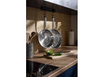 Two SILVERCREST® Stainless Steel Frying Pans hanging in a modern kitchen with a wooden countertop.