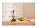 A pink SilverCrest food processor with basil, pine nuts, and cheese on a wooden counter.