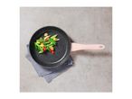 A black speckled frying pan with a pink handle, holding stir-fried vegetables.