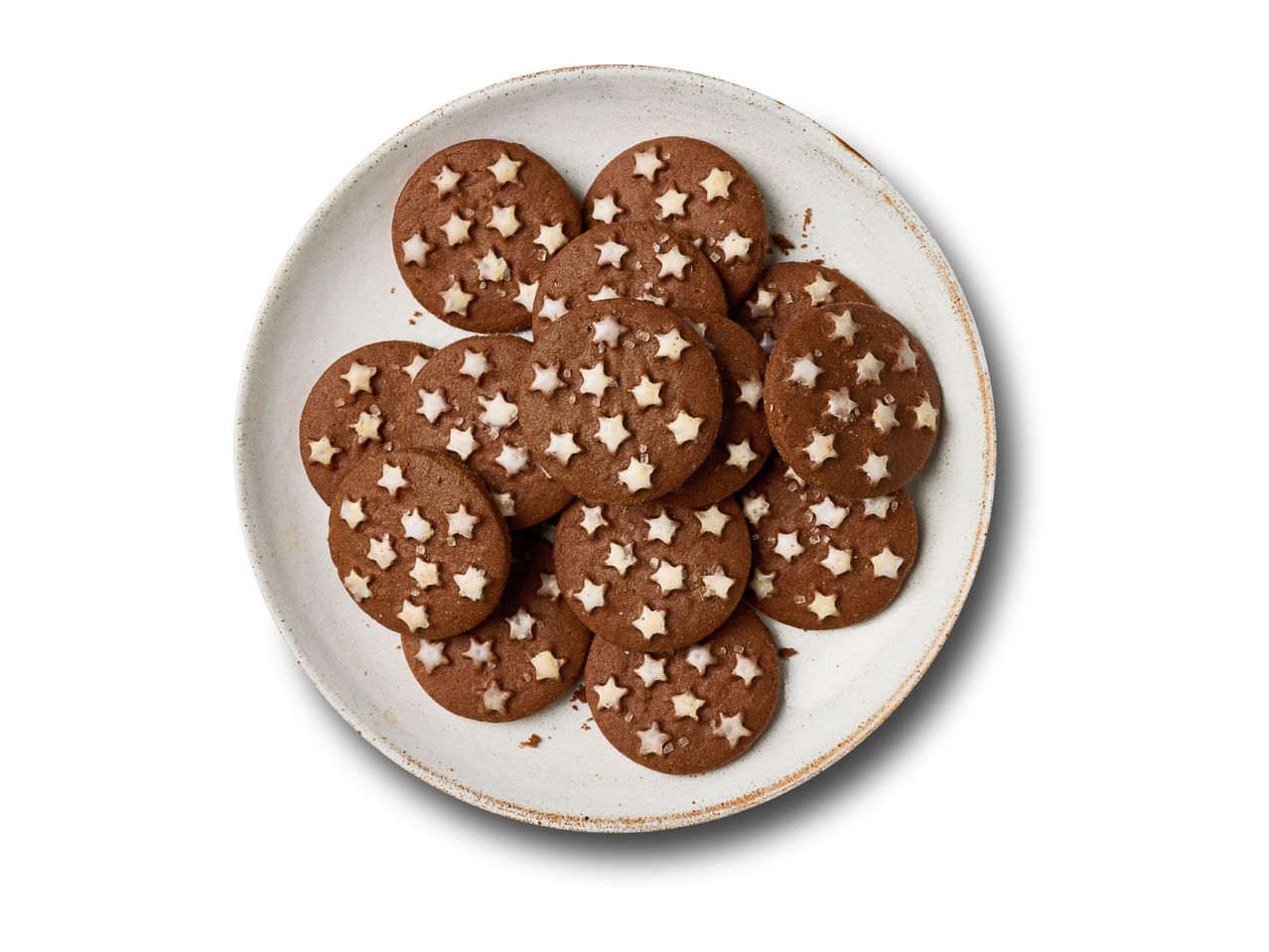 Round chocolate cookies with white star sprinkles on a rustic plate.