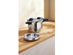 A stainless steel pressure cooker with a blue and black handle, next to a steamer basket.